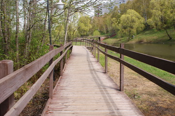 Fototapeta na wymiar Деревянный мостик вдоль городского пруда