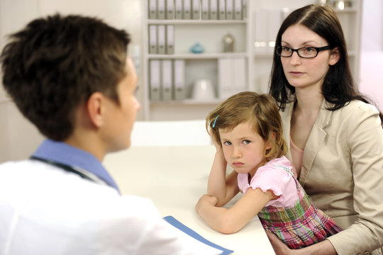 Pediatrician Talking To Mother And Upset Child