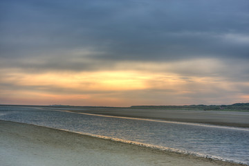 Sunrise above a beach and a creek at ebb tide