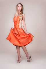 Beautiful young woman wearing a sexy orange evening dress