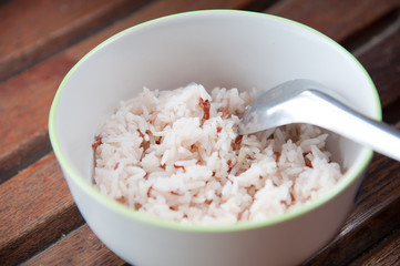 White and brown steamed rice with spoon in white round bowl