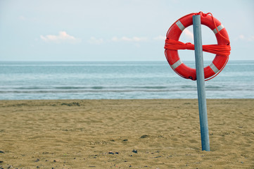 Lifebuoy on a pole along an empty beach
