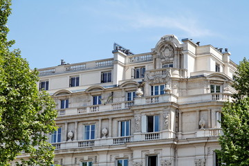 Façade de pierre blanche, arbres verts et ciel bleu.