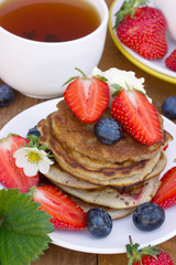 A stack of creamy pancakes with strawberries and blueberries