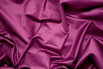 folds of glossy purple satin fabric. Background or texture