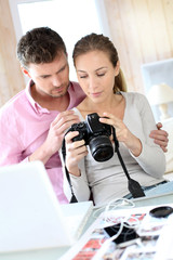 Naklejka premium Couple at home looking at pictures on camera and laptop