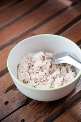 White and brown steamed rice with spoon in white round bowl