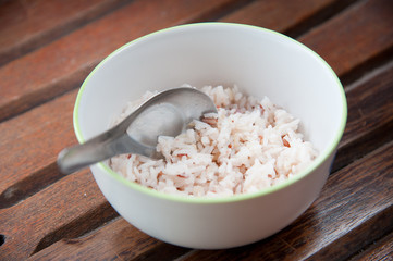 White and brown steamed rice with spoon in white round bowl