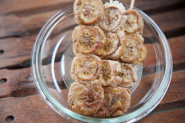 Thailand dessert, baked whole banana on stick and syrup topping