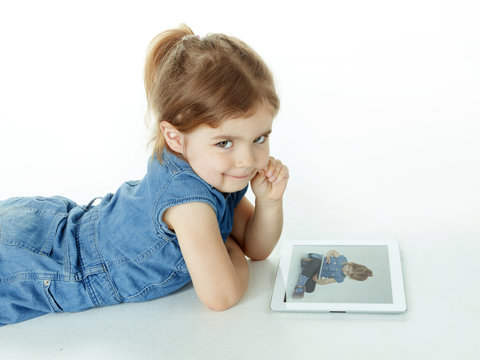 Little girl is watching concentrated photographs on touchpad