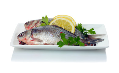 Fresh fishes with lemon and parsley on plate isolated on white