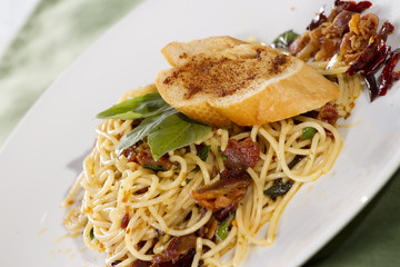 saute pasta with dried chili and piece of bread on top