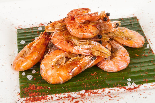 fried black tiger prawns with herbs and spices on banana leaf