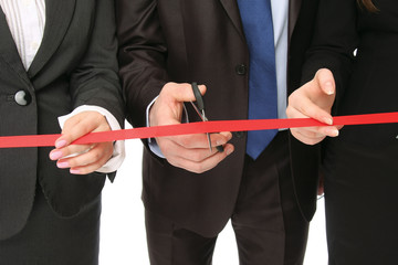 Business people cutting a red ribbon with a pair