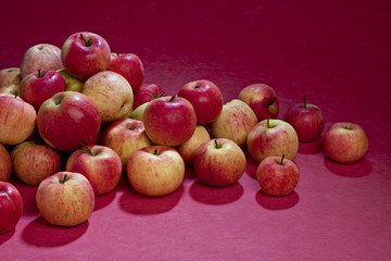 Pile of apples on pink background.