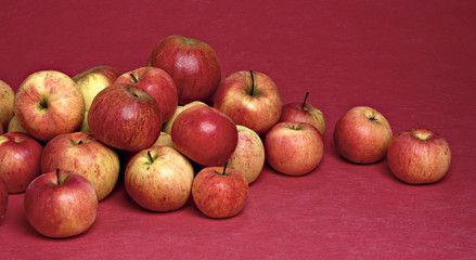Pile of apples on pink background.