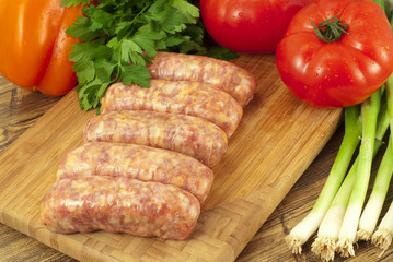 Raw sausages and fresh vegetables on a table