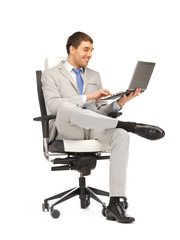 young businessman sitting in chair with laptop
