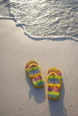 A PAIR OF COLOURFUL FLIP FLOPS AT THE WATER’S EDGE