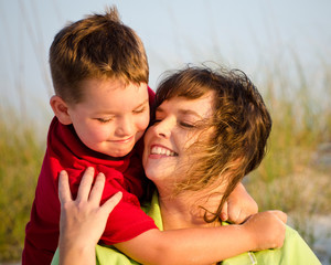 Portrait of happy mother and son hugging at beach