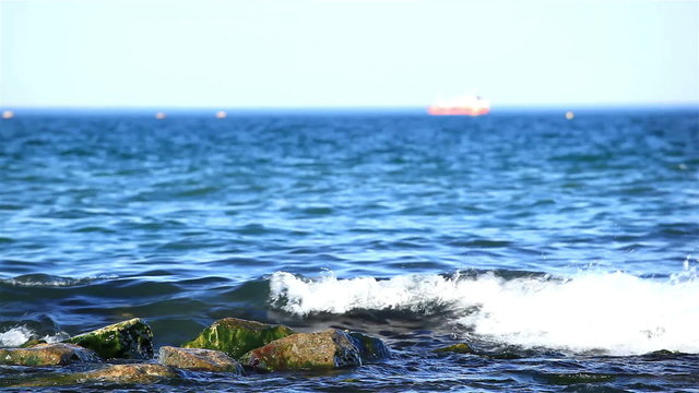 Waves fight about stones to the sea and a ship silhouette