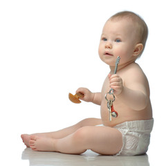 Toddler in diaper playing with wodden spoon and keys