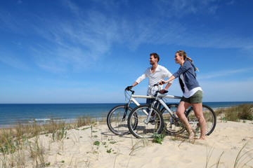 Couple standing on a sand dune with bicycles