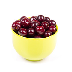 Cherry in green plastic bowl isolated on white background