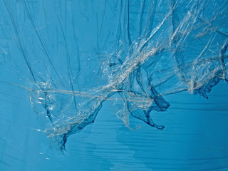 abstract transparent plastic oilskin pieces over blue surface