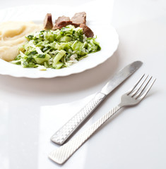 Mashed potato, salad and meat with spoon.