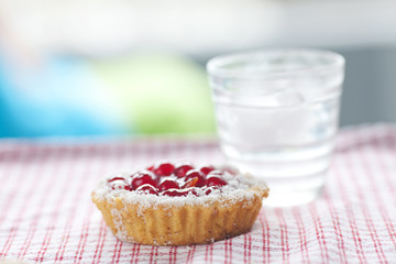 beautiful cake with berries and water on plaid fabric