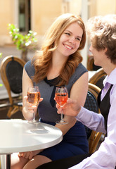 Beautiful couple having a date in a cafe and drinking rose wine