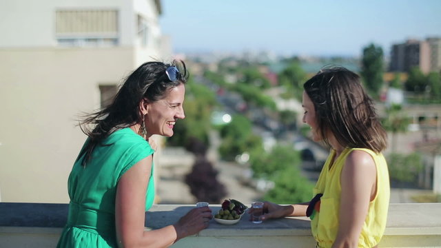 Female friends talking and drinking vodka shots on terrace