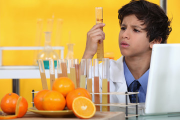 Boy analysing orange juice - obrazy, fototapety, plakaty