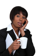 Businesswoman with mug of coffee and telephone