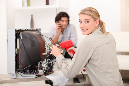 Woman repairing television with soldering iron