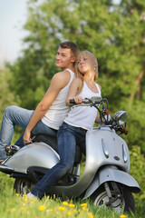Fototapeta na wymiar young loving couple on motorbike / scooter on natural background