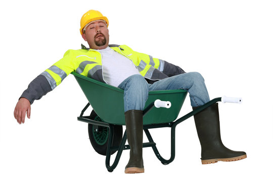 Exhausted builder laying in wheelbarrow