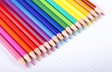Obraz premium Multicolored crayons on white squared paper background.