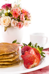 Pancake and strawberry have maple syrup on top with coffee