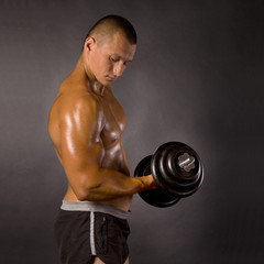 Fototapeta na wymiar Muscled male bodybuilder dumbbell swing