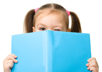 Cute little girl is hiding behind a book