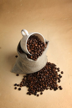 A sack of coffee beans and a cup, from above