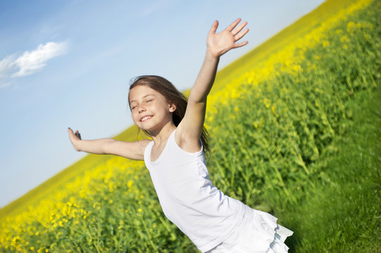 Happy little girl in front of canola field