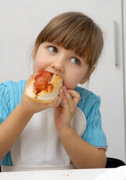 Pequeña niña comiendo perro caliente,hotdog.