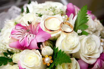 wedding rings of the groom and the bride on a bunch of flowers.