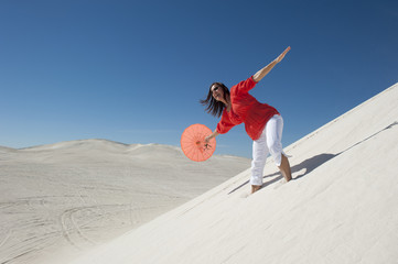 Attractive woman with umbrella on desert sand dune