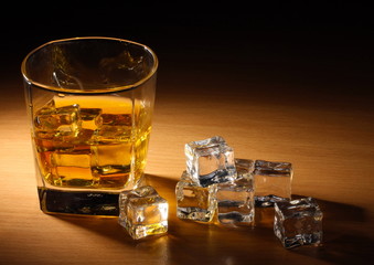 glass of scotch whiskey and ice on wooden table