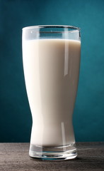 glass of milk on wooden table on blue background