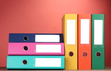 bright office folders on wooden table on red background